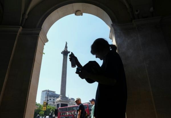 Une femme se protège de la chaleur du soleil, dans l'ombre d'une entrée sur Trafalgar Square, à Londres, le 8 juillet 2026