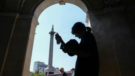 Une femme se protège de la chaleur du soleil, dans l'ombre d'une entrée sur Trafalgar Square, à Londres, le 8 juillet 2026