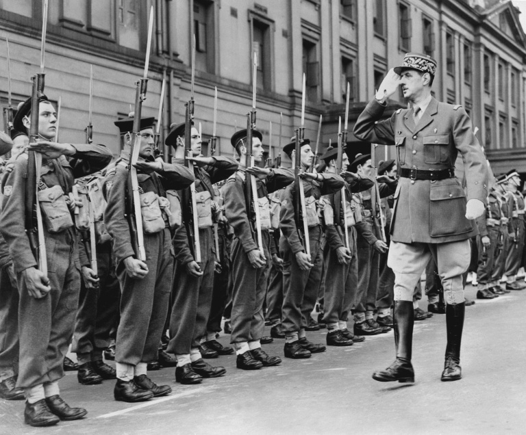 Le chef des Forces françaises libres (FFL), Charles de Gaulle, salue des marins alors qu'il passe en revue les troupes françaises lors du défilé militaire célébrant la fête nationale française à Londres, le 14 juillet 1942, durant la Seconde Guerre mondiale