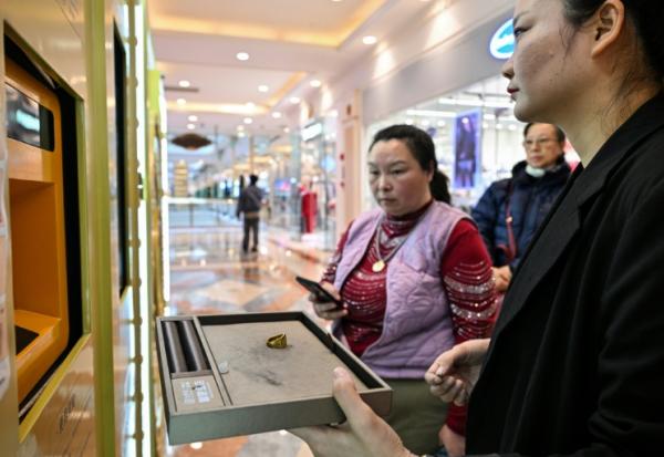 Une employée aide une cliente à vendre un bijou en or dans un automate de Shanghai, en Chine, le 29 janvier 2026