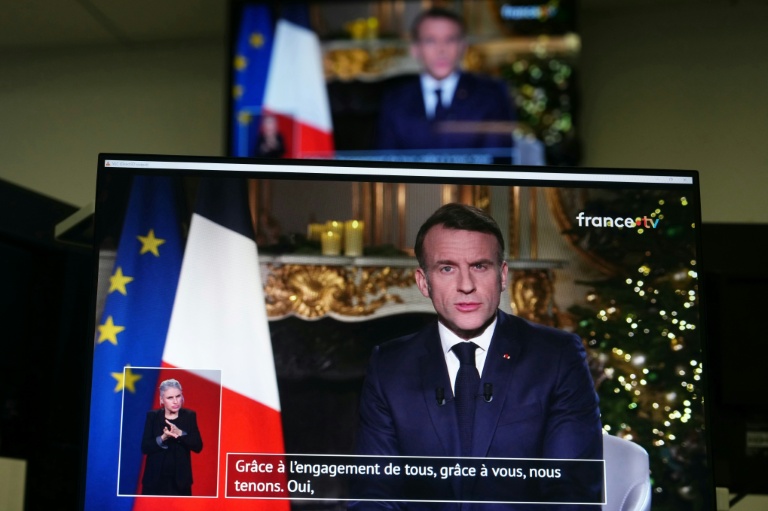 Des écrans de télévision diffusent le discours d'Emmanuel Macron présentant ses vœux de Nouvel An à la nation depuis l'Élysée, à Paris, le 31 décembre 2025