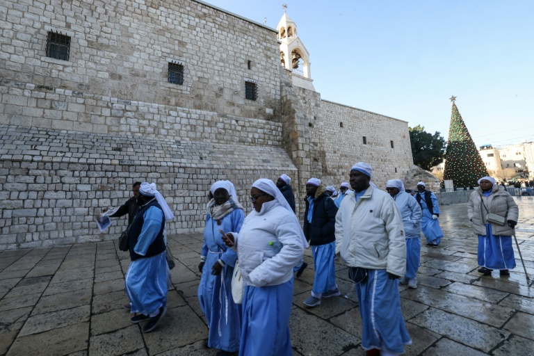 Des religieuses et moines chrétiens passent devant l'église de la Nativité à Bethléem, en Cisjordanie occupée, avant les célébrations de Noël, le 24 décembre 2025
