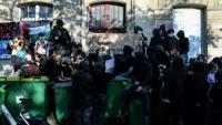 Des manifestants se tiennent debout sur des poubelles empilées à l'entrée du lycée Arago à Paris, le 29 septembre 2026