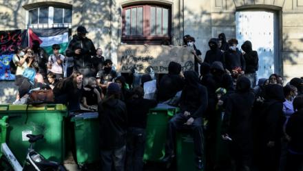 Des manifestants se tiennent debout sur des poubelles empilées à l'entrée du lycée Arago à Paris, le 29 septembre 2026
