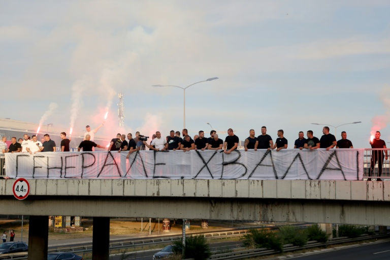 Des personnes rassemblées sur une passerelle d'autoroute tiennent une banderole 