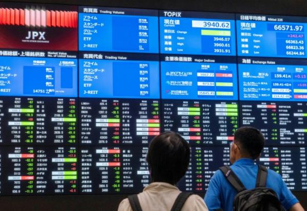 Des visiteurs devant les cours des valeurs à la Bourse de Tokyo le 1er juin 2026