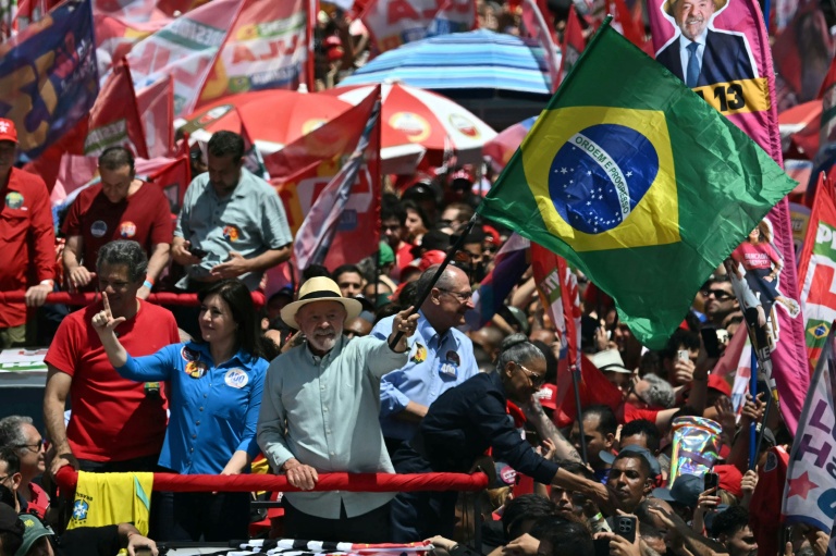 Le président brésilien de gauche Luiz Inacio Lula da Silva (C) agite le drapeau national lors d'un meeting de campagne à la veille du premier tour de la présidentielle, le 3 octobre 2026 à Sao Paulo