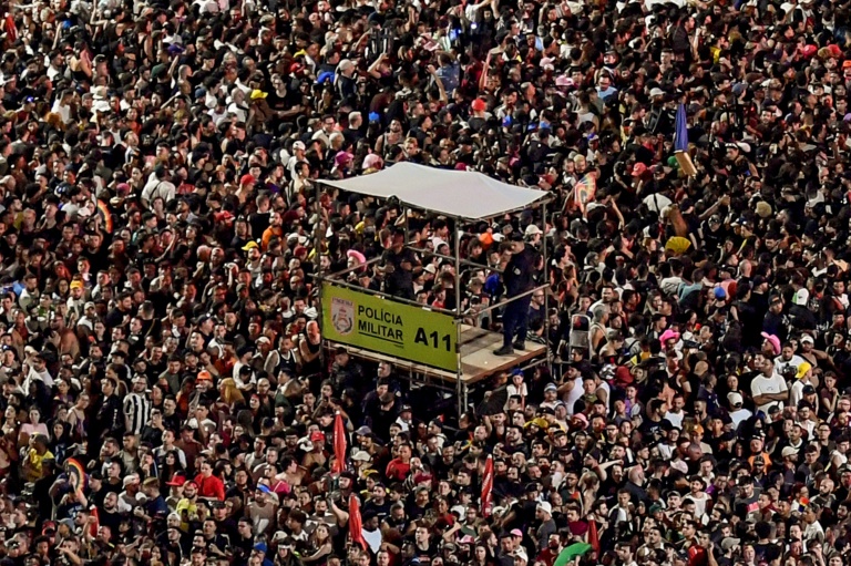 Des officiers de la police militaire se tiennent sur une plateforme surélevée alors que des fans attendent le début du méga-concert gratuit de la pop star américaine Lady Gaga sur la plage de Copacabana à Rio de Janeiro, au Brésil, le 3 mai 2025