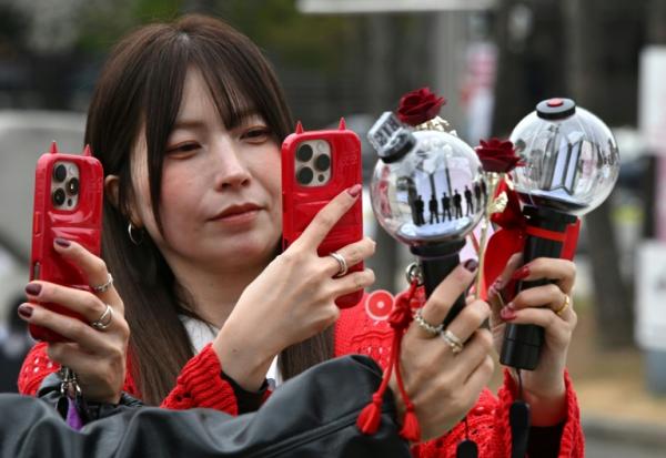 Des fans prennent des photos de bâtons lumineux à l'effigie de BTS à leur arrivée au stade où le groupe de K-pop se produira, à Goyang, le 9 avril 2026