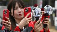 Des fans prennent des photos de bâtons lumineux à l'effigie de BTS à leur arrivée au stade où le groupe de K-pop se produira, à Goyang, le 9 avril 2026