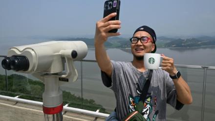 Un touriste prend un selfie avec une tasse Starbucks devant la Corée du Nord depuis une plate-forme d'observation sud-coréenne située à l'Écoparc de la Paix d'Aegibong, à Gimpo, le 1er juillet 2026 