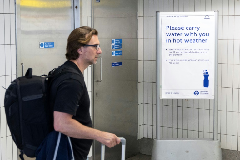 Un homme passe devant un panneau conseillant aux voyageurs d'emporter une bouteille d'eau avec eux, à la gare de Hammersmith, dans l'ouest de Londres, le 22 juin 2026