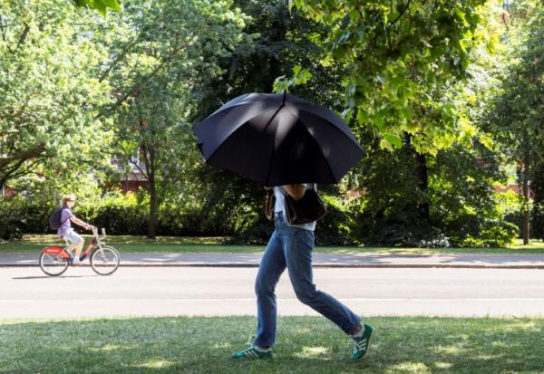 Une personne s'abrite du soleil avec un parapluie, le 22 juin 2026 à Hyde Park, à Londres