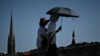 Des passants se protègent de la chaleur avec un parapluie, le 6 juillet 2026 à Bordeaux 