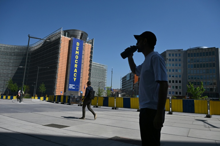 Un homme boit de l'eau, à l'ombre près du bâtiment de la Commission européenne, lors d'une vague de chaleur à Bruxelles, le 25 juin 2026