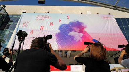 Des employés installent l'affiche officielle du 78e Festival de Cannes sur la façade du Palais des Festivals à Cannes, dans le sud-est de la France, le 11 mai 2025