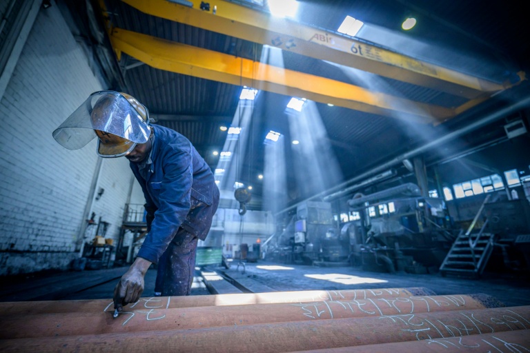 Un ouvrier appose des étiquettes sur des barres en alliage de cuivre fraîchement coulées à l'usine de tubes MPG (Mendener Präzisionsrohr GmbH) de Menden, dans l'ouest de l'Allemagne, le 18 juin 2026