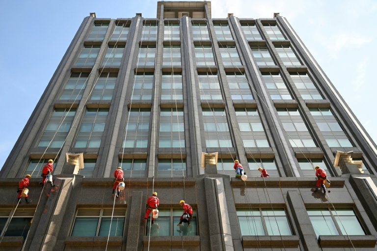 Des laveurs de vitres sur la façade d'un immeuble à Pékin, le 20 octobre 2025