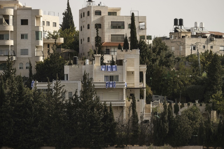 Des drapeaux israéliens placés sur des balcons après que l'armée israélienne a forcé des Palestiniens à évacuer le quartier d'Ein Deir Baha, dans la ville d'Hébron, en Cisjordanie occupée, le 24 octobre 2026 
