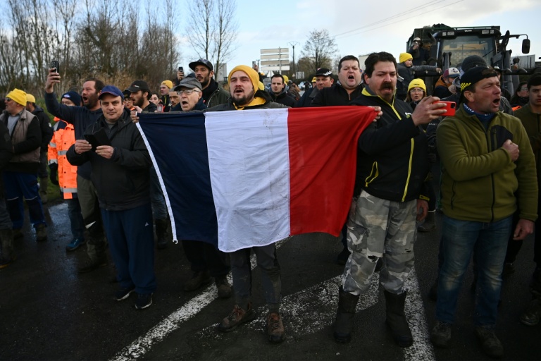 Des agriculteurs tiennent un drapeau français lors d'une intervention des forces de l'ordre pour mettre fin au blocage du dépôt de carburant de Bassens, près de Bordeaux, le 10 janvier 2026