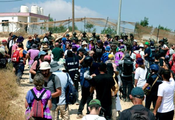 Des Palestiniens et des militants rassemblés pour manifester contre des colons israéliens qui assiègent la maison d'une famille palestinienne dans le village de Qusra, au sud de la ville de Naplouse, en Cisjordanie occupée, le 14 août 2026