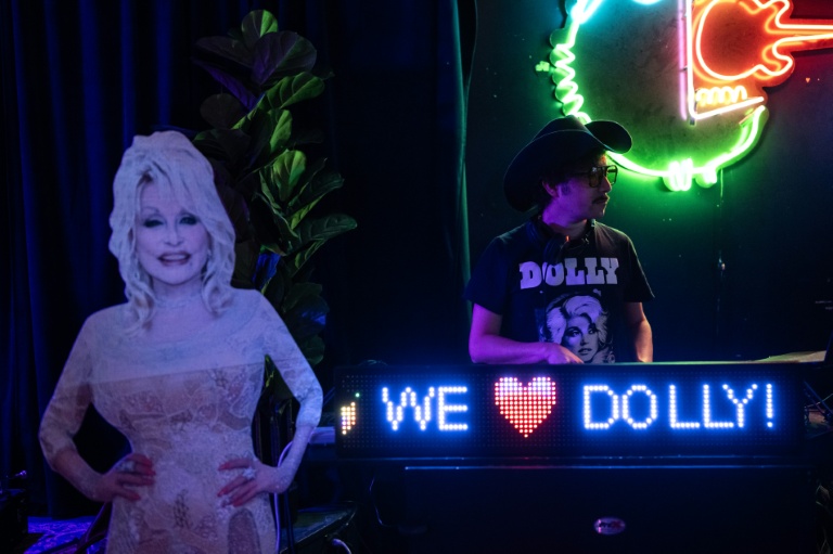 Un DJ joue de la musique à côté d’une silhouette en carton de la stard américaine de la country Dolly Parton, lors d’une soirée en son honneur dans un bar de Houston, au Texas, le 26 août 2026
