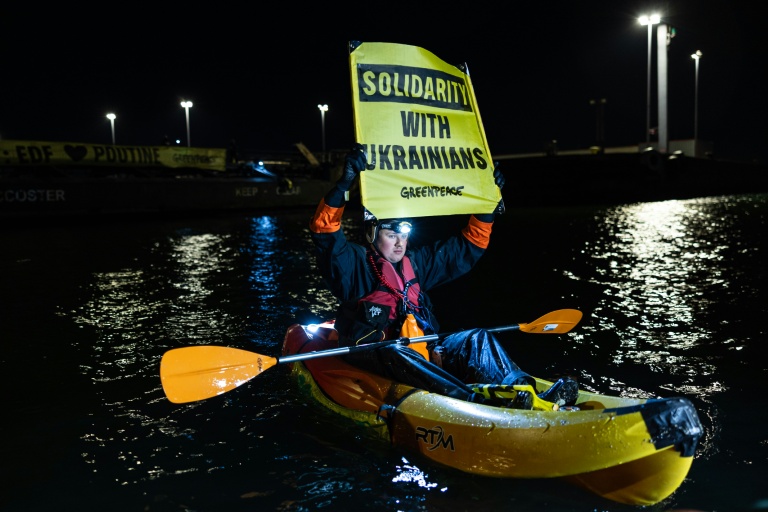 Un militant de Greenpeace brandit une affichette lors d'une action pour dénoncer le commerce d'uranium entre la Russie et la France le 2 mars 2026 dans le port de Dunkerque