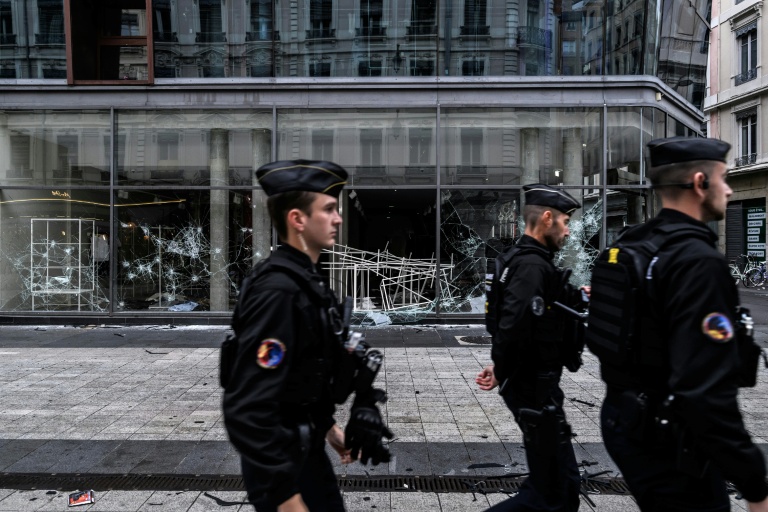 Des gendarmes en patrouille passent devant des boutiques endommagées à Lyon, au lendemain d'une manifestation contre la vie chère, le 18 octobre 2026
