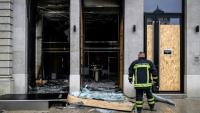 Un pompier devant les vitrines brisées d'un commerce, pillé et vandalisé, au lendemain d'une manifestation contre la vie chère à Lyon, le 18 octobre 2026