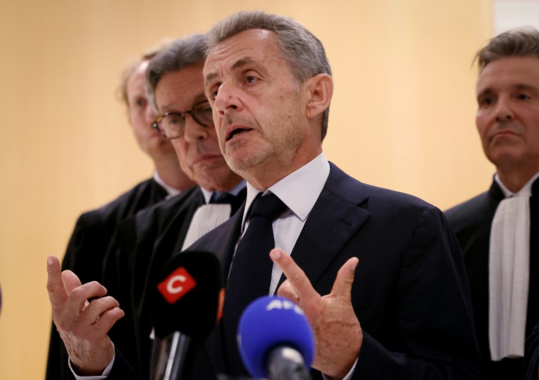 L'ancien président Nicolas Sarkozy (C) s'adresse à la presse aux côtés de son avocat Jean-Michel Darrois (2e g) après le verdict du procès libyen pour financement illégal de sa campagne de 2007, au tribunal de Paris, le 25 septembre 2025