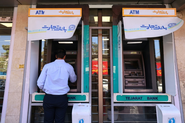Un homme retire de l'argent à un distributeur automatique de la banque Tejarat, dans une rue à Téhéran, le 25 mai 2026 en Iran