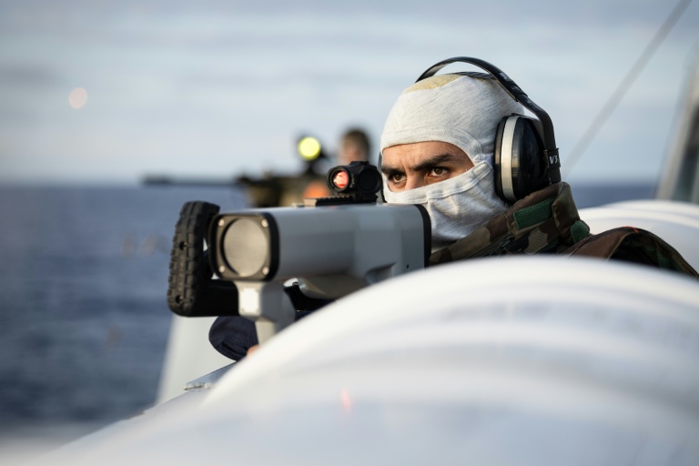 Un marin français tient un pointeur infrarouge pour désigner des cibles d'urgence, tout en recherchant des drones hostiles, à bord de la frégate française 