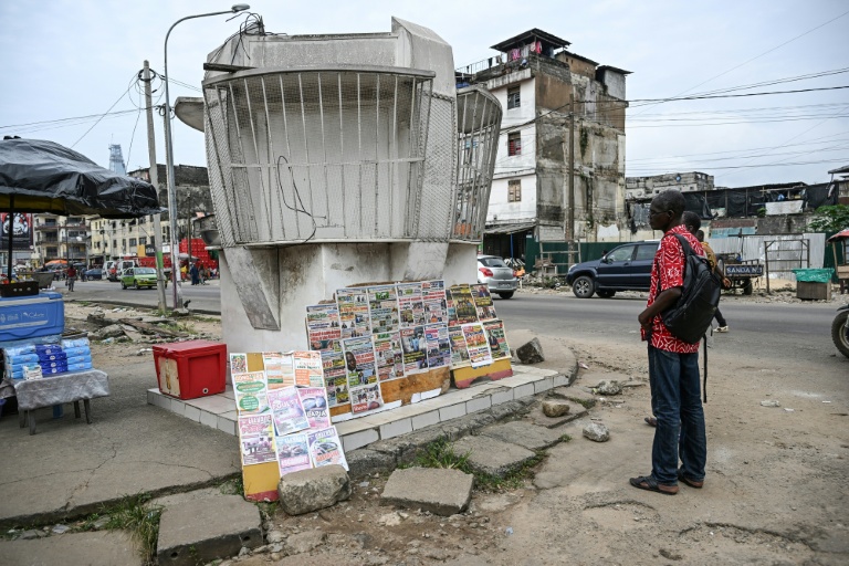 Des passants lisent les gros titres des journaux ivoiriens au bord d'une rue d'Ajamé, un quartier populaire d'Abidjan (Côte d'Ivoire), le 9 juin 2026