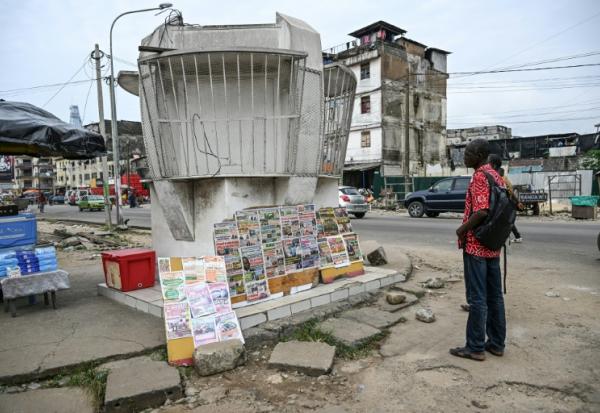 Des passants lisent les gros titres des journaux ivoiriens au bord d'une rue d'Ajamé, un quartier populaire d'Abidjan (Côte d'Ivoire), le 9 juin 2026