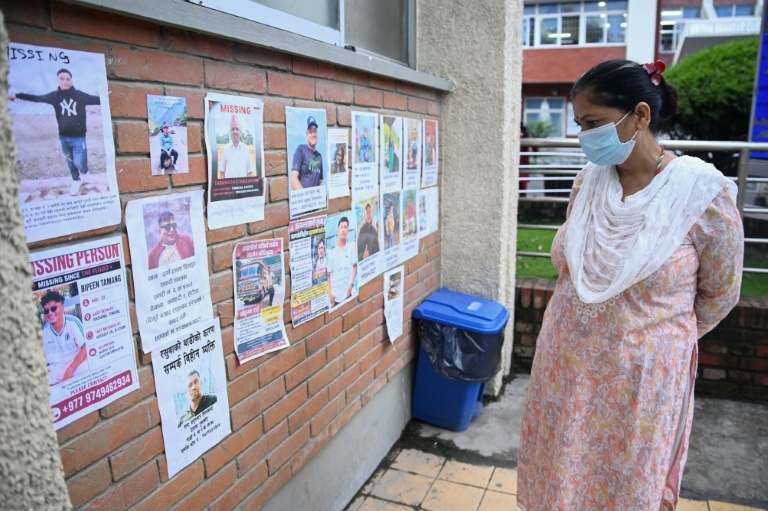 Une femme regarde les photos de personnes portées disparues dans la crue destructrice qui a fait plus de 600 morts à la frontière entre le Népal et la Chine, le 29 août 2026 à Katmandou