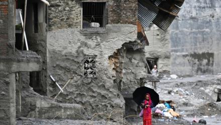 Une femme marche au milieu des ruines laissées par des crues soudaines dans le district de Nuwakot, au Népal, le 1er septembre 2026