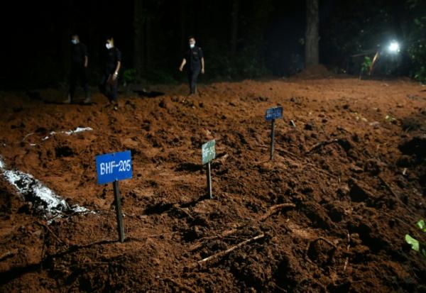 Des agents de police marchent à proximité de tombes de victimes non identifiées de la crue dévastatrice, le 30 août 2026 à Devghat au Népal