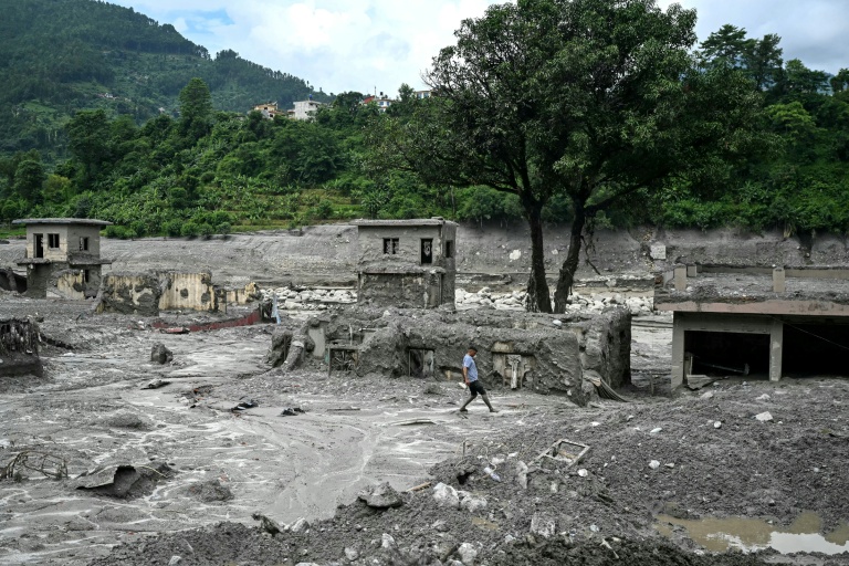 Un homme marche au milieu des décombres après la crue destructrice dans l'Himalaya, le 30 août 2026 à Trishuli, dans le district népalais de Nuwakot 