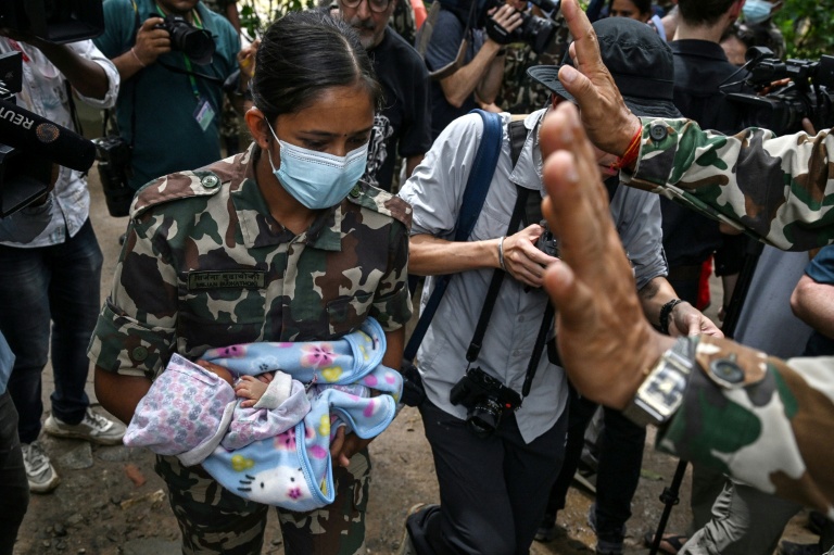Une militaire porte un enfant secouru après la crue destructrice qui a fait au moins 633 morts à la frontière entre le Népal et la Chine, le 29 août 2026 au camp de Trishuli, dans le district népalais de Nuwakot  