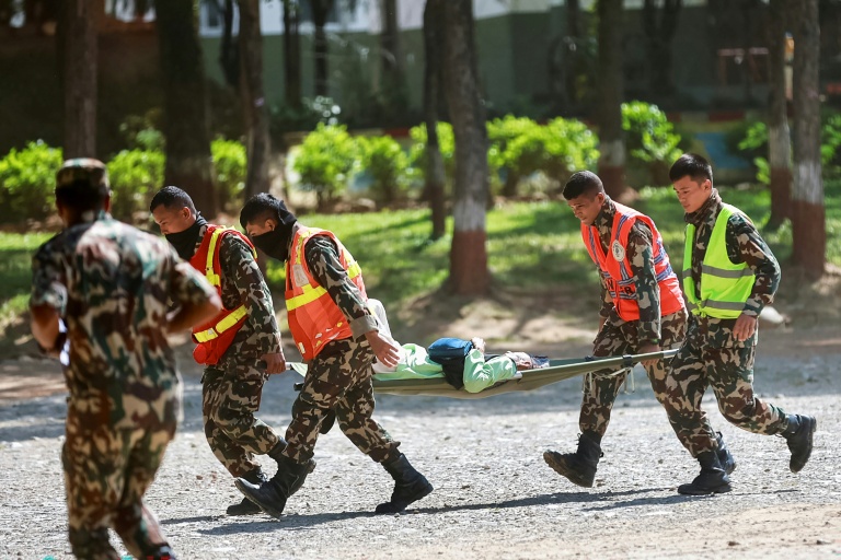 Des militaires népalais transportent une personne secourue, le 28 août 2026, à la suite des coulées de boue survenues à la frontière sino-népalaise l'avant veille