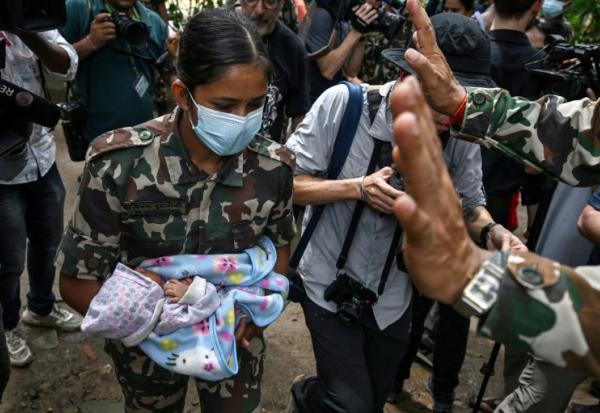 Une militaire porte un enfant secouru après la crue destructrice qui a fait au moins 633 morts à la frontière entre le Népal et la Chine, le 29 août 2026 au camp de Trishuli, dans le district népalais de Nuwakot  