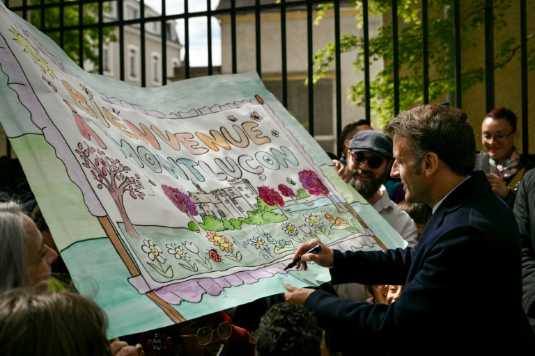 Le président Emmanuel Macron signe un dessin réalisé par des écolisiers à Montluçon, le 22 avril 2026 dans l'Allier