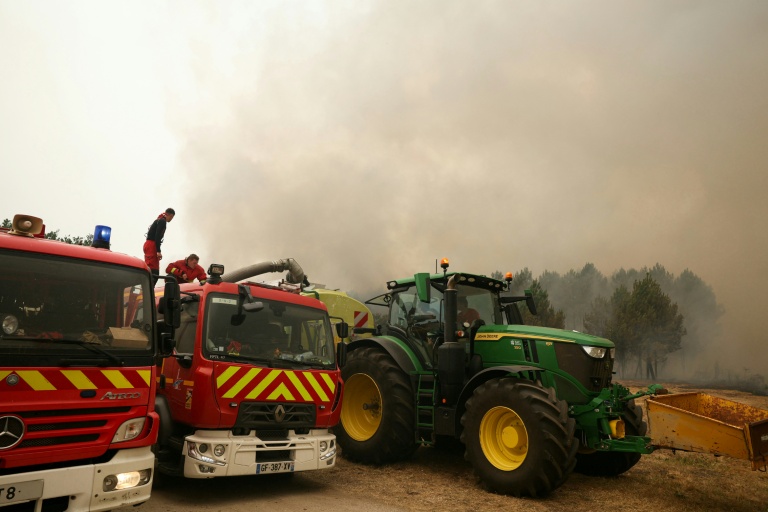 Des sapeurs-pompiers de la Brigade de sapeurs-pompiers de Paris ravitaillent leurs véhicules en eau à partir de la cuve du tracteur d'un agriculteur lors d'une intervention à Marcheprime, à l'ouest de Bordeaux, le 26 juillet 2026