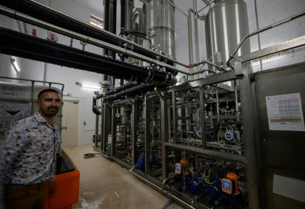 Un employé pose à côté d'une unité de désalcoolisation du vin dans le laboratoire du Chai sobre, le 25 juin 2025 à à Vic-Fezensac, dans le Gers 