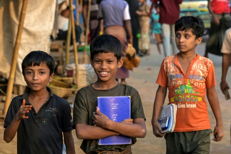 Des enfants réfugiés rohingyas portent leurs manuels scolaires au camp de réfugiés de Kutupalong, le 17 décembre 2025 à Ukhia, au Bangladesh
