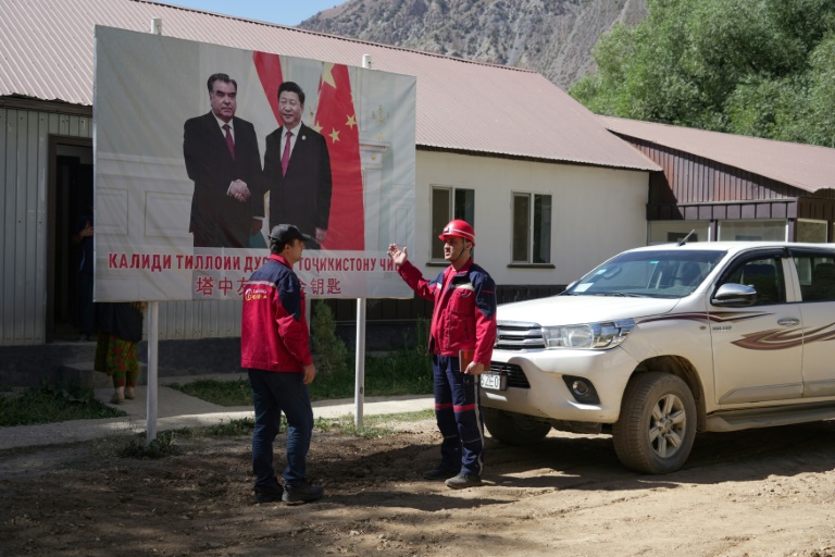 Des employés de l'entreprise Talco Gold, devant une affiche du président chinois Xi Jinping (d) et du président tadjik Emomali Rakhmon à la mine d'antimoine de Saritag, dans l'ouest du Tadjikistan, le 26 août 2025