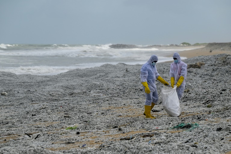 Des soldats de la Marine sri-lankaise nettoient une plage polluée par des tonnes de granulés plastiques industriels (GPI) provenant d'un porte-conteneurs en feu au large de Colombo, le 28 mai 2021