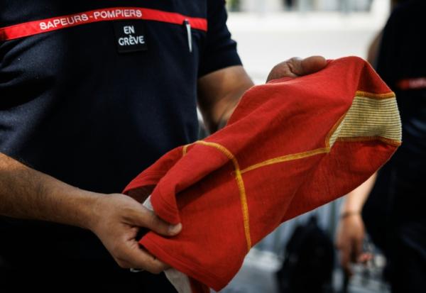 Un pompier avec "en grève" scratché sur la poitrine, devant  l'hôtel de Beauvau, à Paris, le 13 août 2026