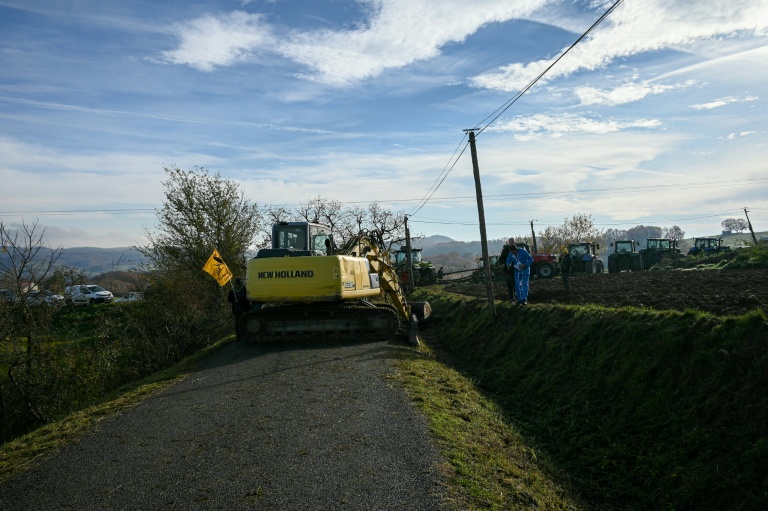 Un agriculteur, à l'aide d'un tracteur, bloque la route avec des troncs d'arbres lors d'une manifestation pour empêcher l'abattage d'un troupeau de 200 vaches, suite à la détection de la dermatose nodulaire contagieuse (DNC) aux Bordes-sur-Arize, le 11 décembre 2025 en Ariège