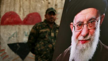 Un membre des Forces de mobilisation populaire irakiennes se tient derrière un portrait du guide suprême iranien défunt Ali Khamenei, à la veille de son cortège funère, au mausolée de l'imam Hussein à Karbala, en Irak, le 7 juillet 2026